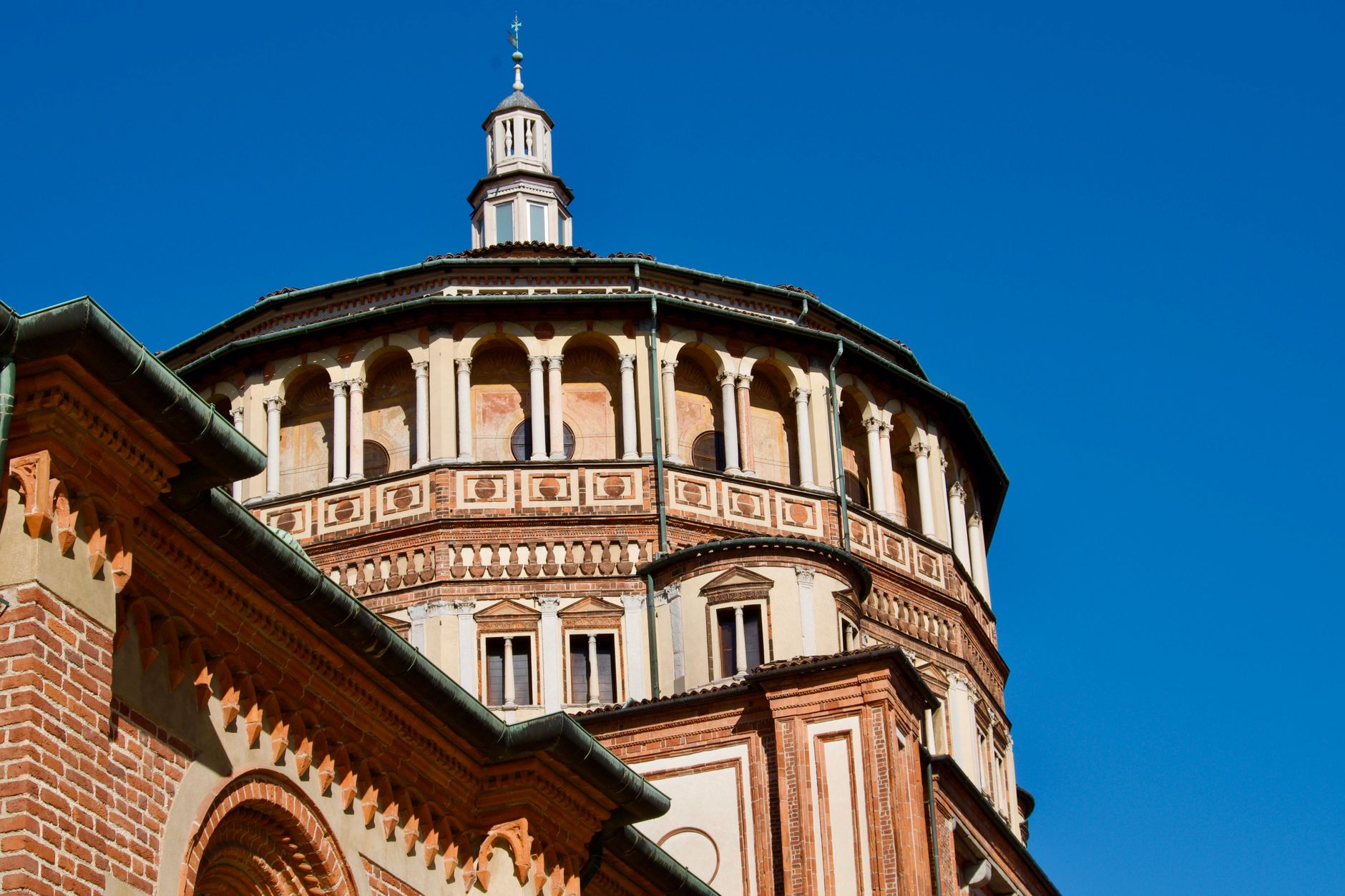Close-up of Santa Maria delle Grazie's dome in Milan under a clear blue sky.