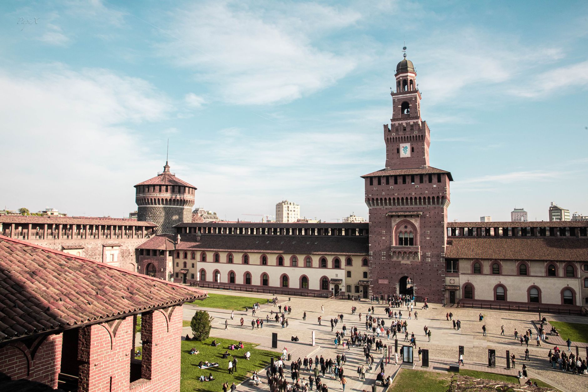 Aerial view of the historic Sforza Castle courtyard teeming with visitors in Milan, Italy.